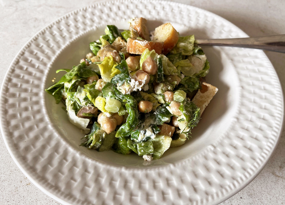 Image of a white bowl with salad, croutons and a fork.